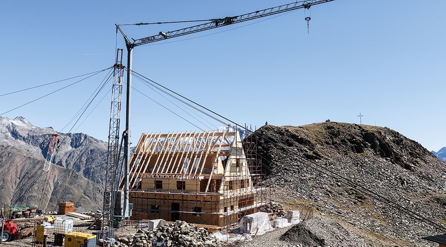 Die Wände der Heilbronner Hütte stehen, dahinter das Gipflekreuz