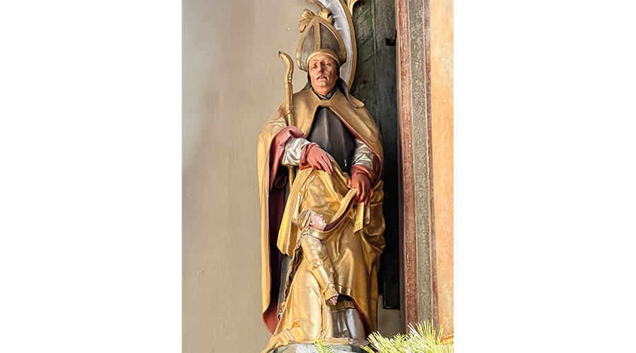 Die Seitenstatue des hl. Remigius am Hochaltar. Er legt eine Stola um den Hals eines vor ihm knieenden Mädchens. Dies kann als Patronat gegen Halsweh gedeutet werden.  (Foto: Peter Tscholl)